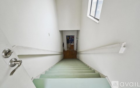 A staircase with a metal railing and a white wall.