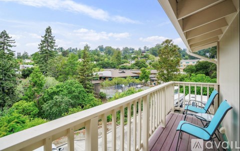 A balcony with chairs overlooks a green landscape.
