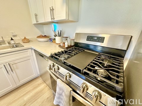 A modern kitchen with a stainless steel stove and white cabinets.