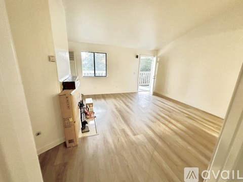 A room with wooden flooring and a window with a view of a fence.