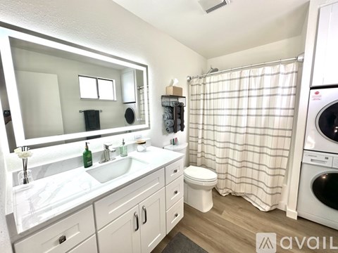 A bathroom with a white sink, toilet, and a washer and dryer.