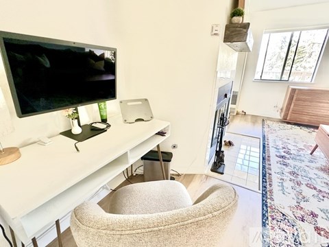 A cat tree is in the corner of a room with a television and a cat bed.