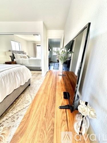 A television is on a wooden stand in a bedroom.