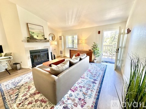 A living room with a grey couch and a fireplace.