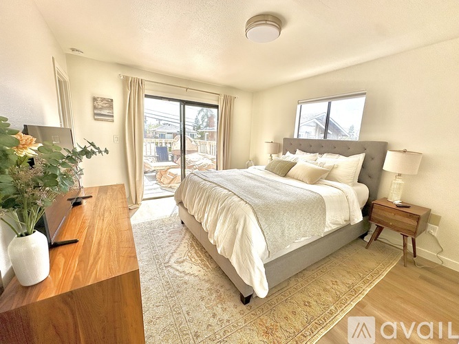 A bedroom with a large bed and a wooden table with a vase of flowers on it.