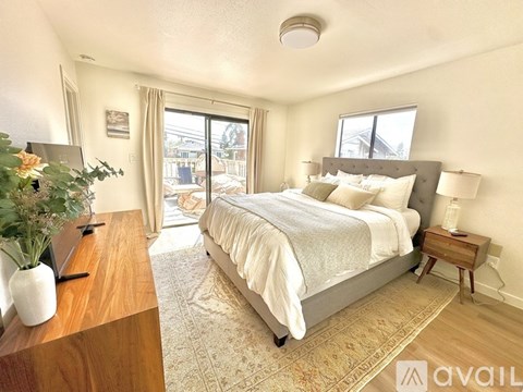 A bedroom with a large bed and a wooden table with a vase of flowers on it.