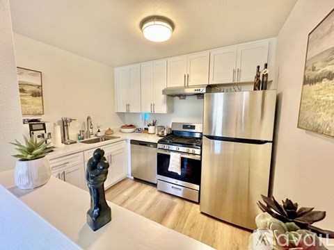 A kitchen with a refrigerator, oven, and sink.