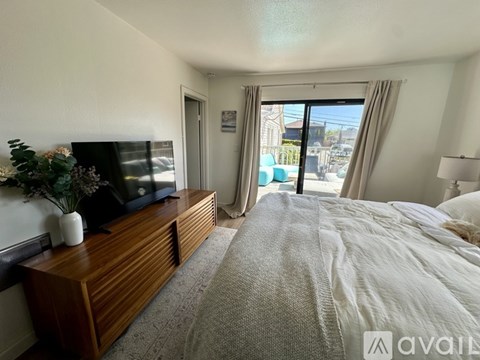 A bedroom with a large bed, a wooden dresser, and a flat-screen TV.