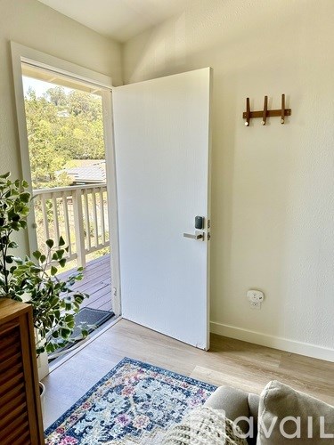 A white door is open to a balcony with a view of trees.