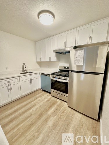 A kitchen with white cabinets and a wooden floor.