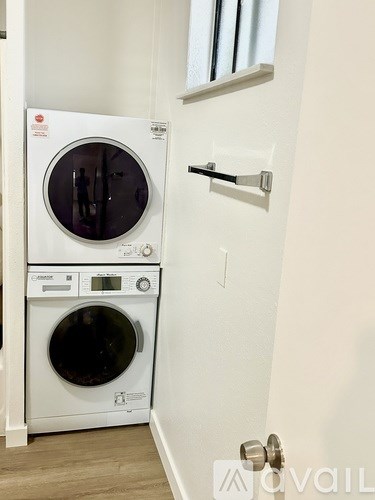 A white front loading washing machine and dryer in a small room.
