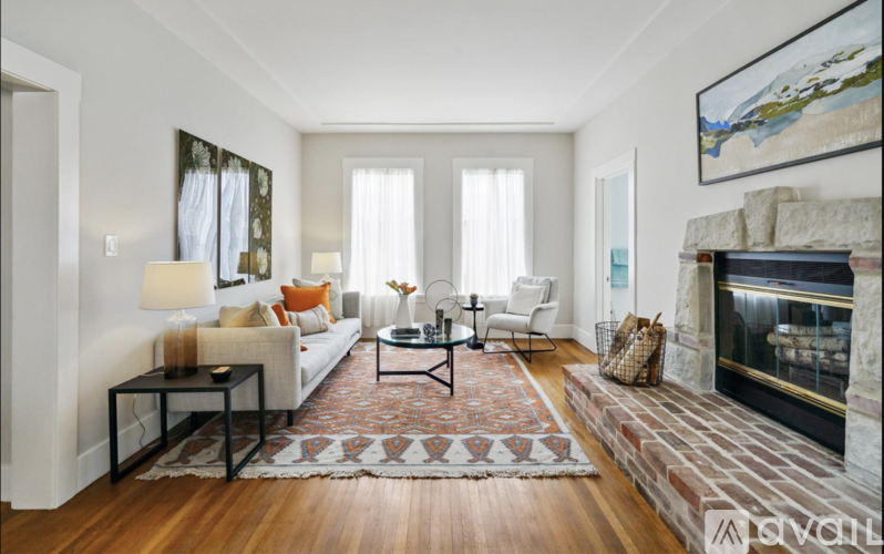 A living room with a fireplace and a rug on the floor.