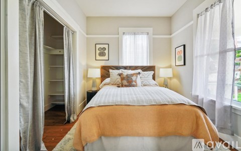 A bedroom with a large bed and a window with curtains.