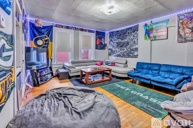 A room with a blue couch, a grey bean bag chair, and a green rug with the words "meet grass" written on it.