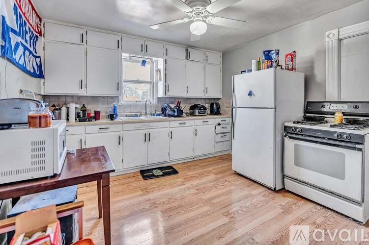 A kitchen with white appliances and wooden floors is available for rent.
