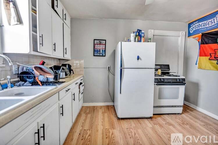 A kitchen with a white fridge and wooden floors.