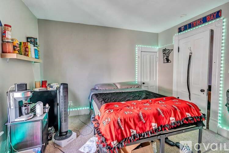 A room with a bed, a shelf with various items, and a wall with LED lights.