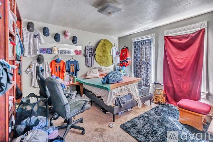 A room with a bed, desk, chair, and sports equipment.