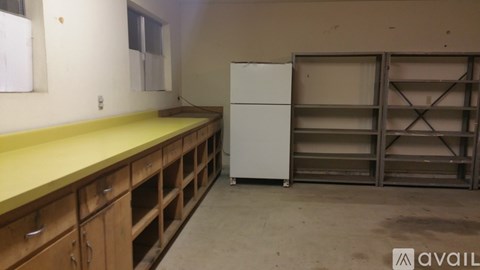 A kitchen with a white fridge and wooden drawers.