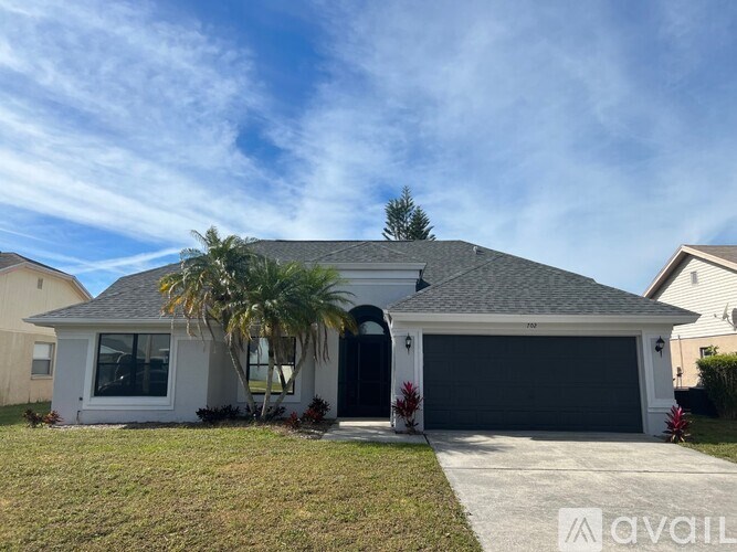 A house with a garage and a palm tree in front.