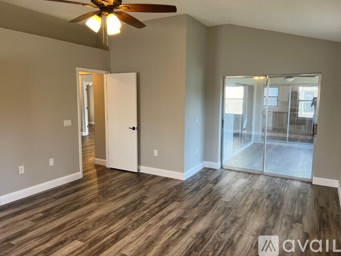 A room with a ceiling fan and wood flooring.