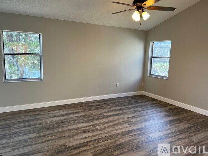 A room with a ceiling fan and two windows.