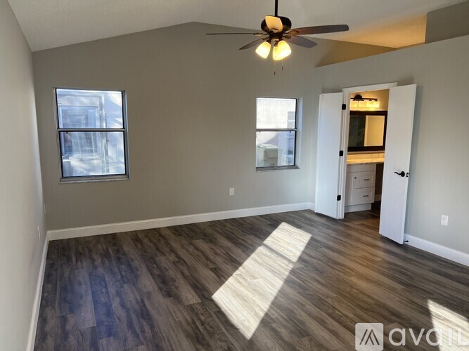 A room with a ceiling fan and a rug on the floor.
