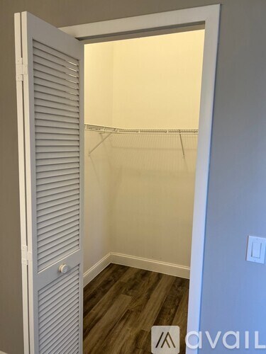 A room with a white door and wooden floor.