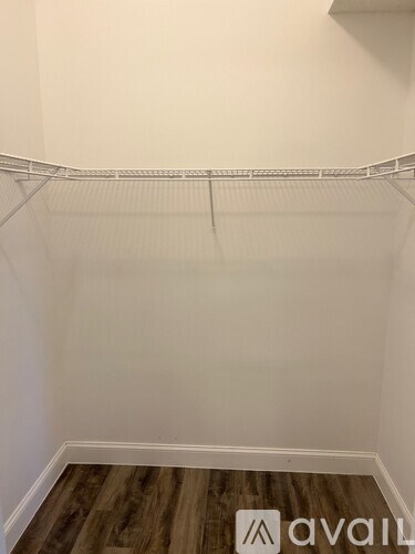 A white wall with a wooden floor and a metal shelf.