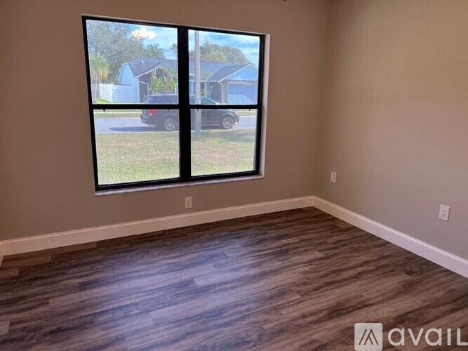 A room with a large window and wooden flooring.