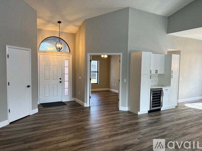A spacious living room with wood flooring and a large arched window.