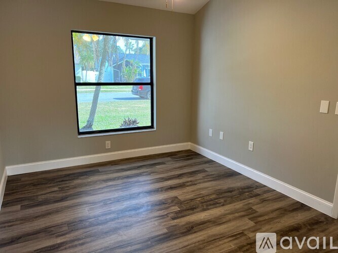 A room with a large window and wooden flooring.
