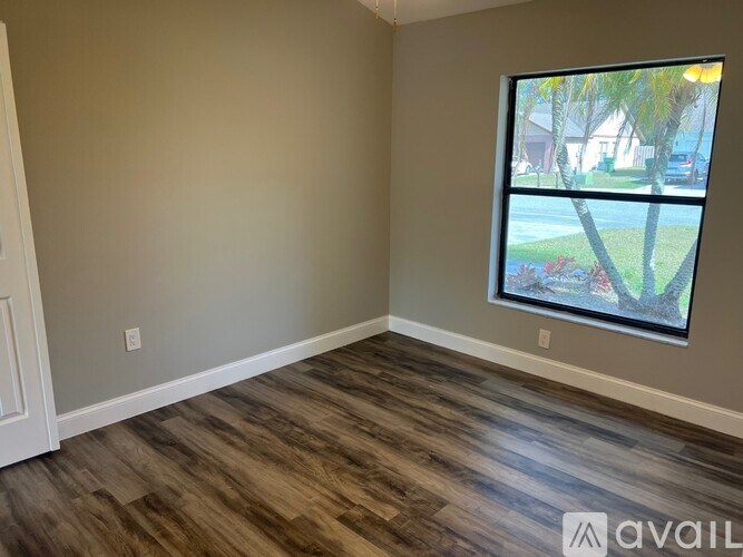 A room with a large window and wooden flooring.