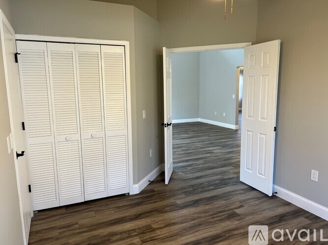 A room with white doors and wooden flooring.