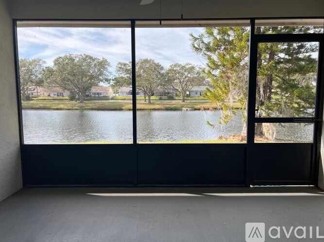 A room with a large window overlooking a lake and trees.