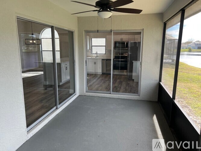A room with a ceiling fan and sliding glass doors leading to a backyard.