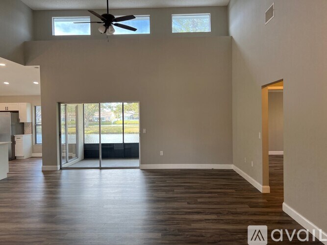 A spacious room with a ceiling fan and sliding glass doors leading to a balcony.