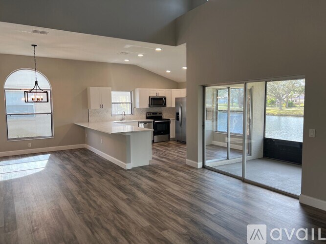 A spacious kitchen with a large island and a view of the outdoors through a sliding glass door.