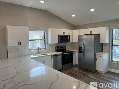 A kitchen with white cabinets and a marble countertop.