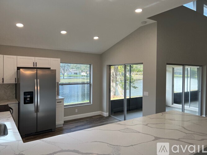 A modern kitchen with a refrigerator, cabinets, and a marble floor.