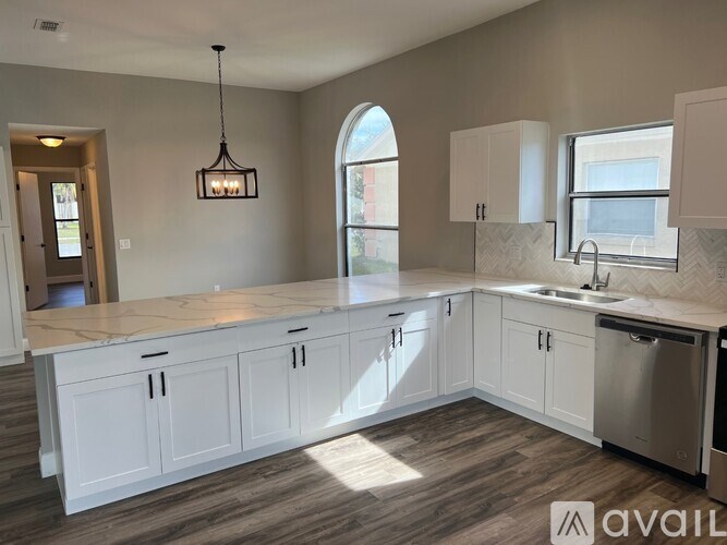 A modern kitchen with white cabinets and a marble countertop.