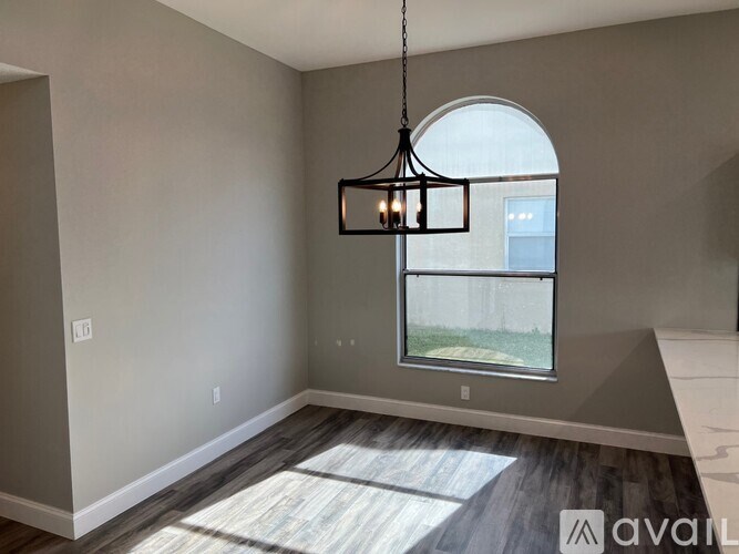 A room with a large window and a hanging light fixture.