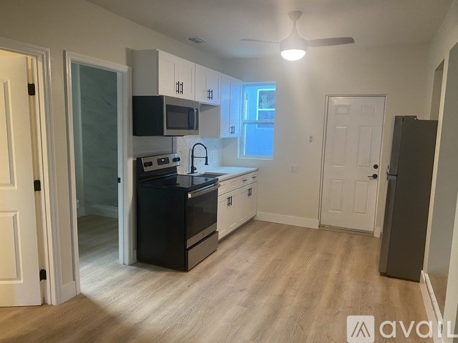 A kitchen with black appliances and white cabinets.