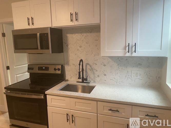 A kitchen with white cabinets and a black stove top oven.