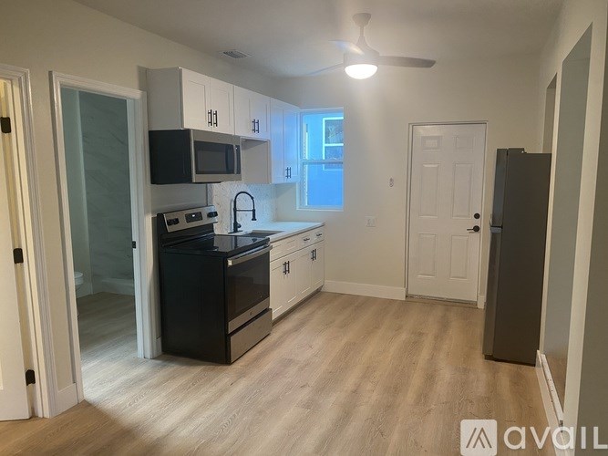 A kitchen with black appliances and white cabinets.