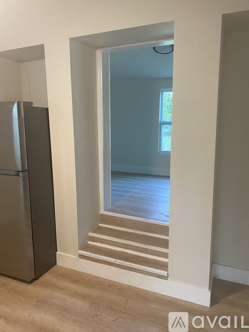 A kitchen with a fridge and a doorway leading to a hallway.