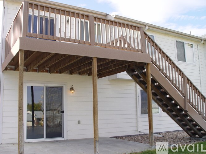 A wooden deck with a staircase leading to a white house.