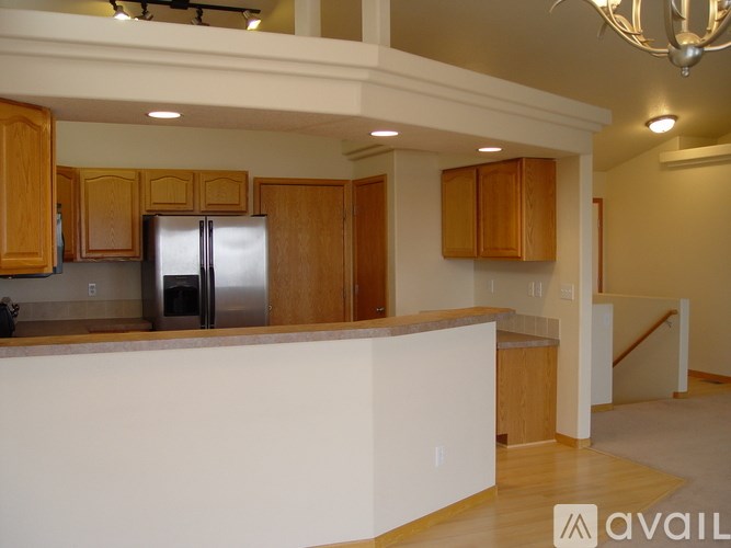 A kitchen with wooden cabinets and a stainless steel refrigerator.