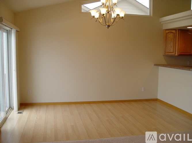 A room with wooden flooring and a chandelier hanging from the ceiling.