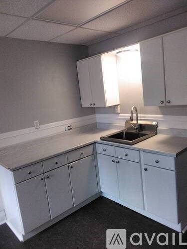 A kitchen with white cabinets and a stainless steel sink.
